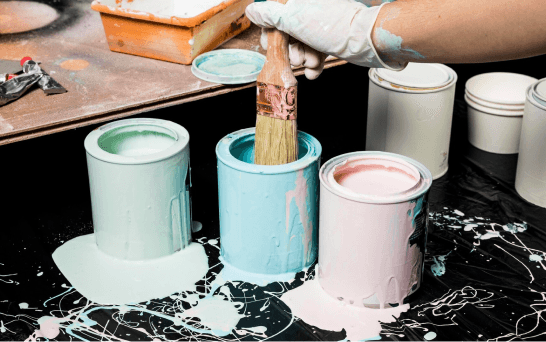 Dipping paintbrush in paint cans